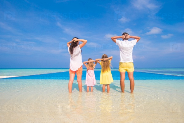 Rear view of young beautiful family on white tropical beach