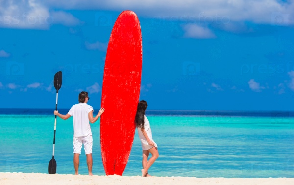 Young couple with red surfboard during tropical vacation