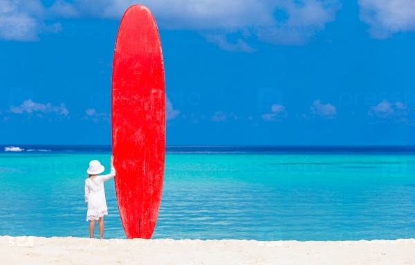 Adorable little girl with red big surfboard during tropical vacation