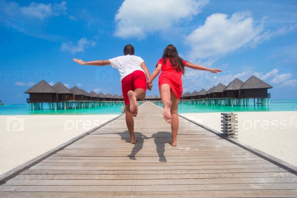 Young couple on tropical beach jetty at perfect island