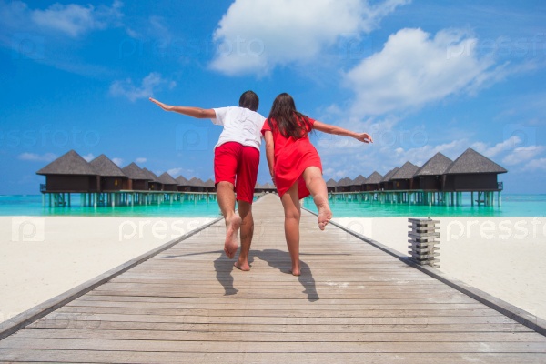 Young couple on tropical beach jetty at perfect island