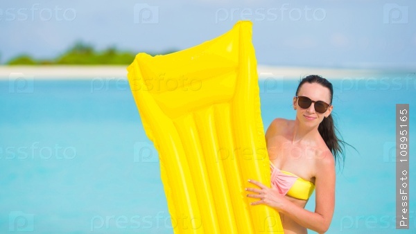 Young happy woman relaxing with air mattress on the beach