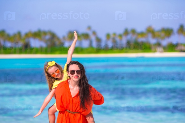 Little adorable girl and happy mom having fun during beach vacation