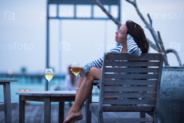 Young woman with a glass of white wine at evening