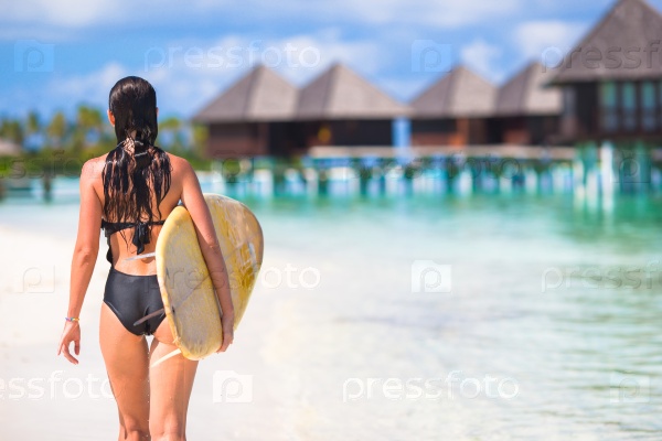 Happy young surf woman at the beach with a surfboard