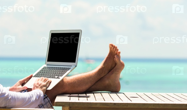 Young man with tablet computer during tropical beach vacation