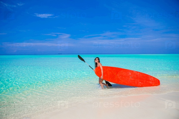 Happy young surf woman at the beach with a surfboard and paddle, stock photo