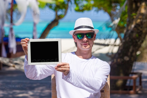 Young man on the beach with tablet computer. Showing screen digital pc, stock photo