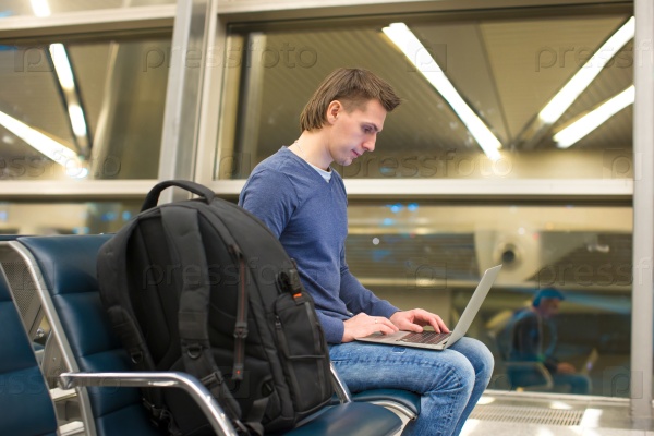 Young man with laptop and luggage at airport