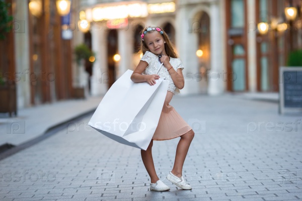 Adorable little girl walking with shopping bags in Paris outdoors, stock photo