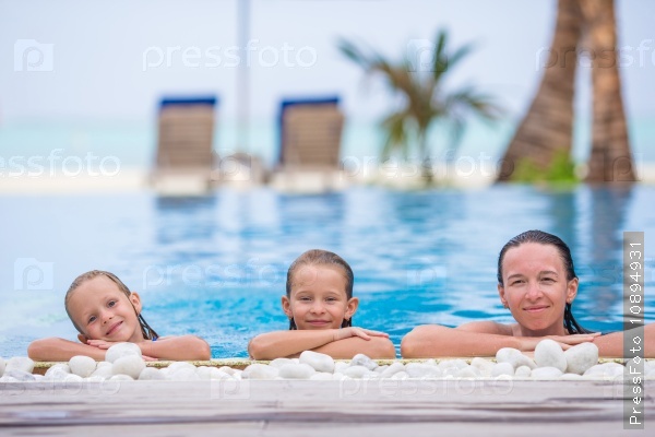 Little cute girl and happy mom enjoying vacation in outdoor swimming pool