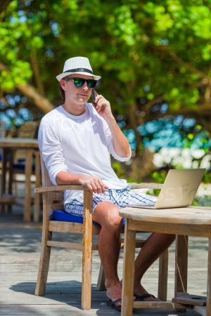 Young business man calling by cell phone on white beach