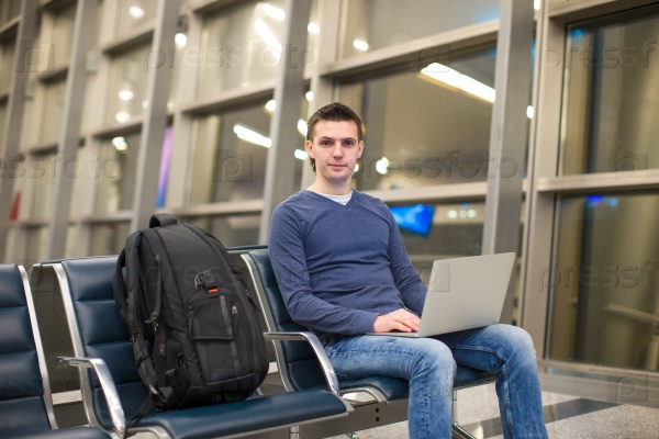 Young man with laptop and backpack at airport