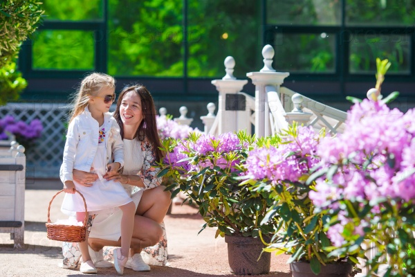 Adorable little girl and young mom enjoying warm day in tulip garden