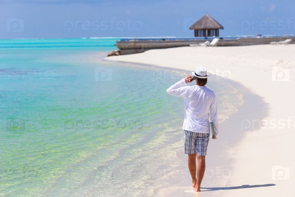 Young business man calling by cell phone on white beach, stock photo