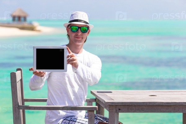 Young man on the beach with tablet computer. Showing screen digital pc, stock photo