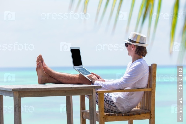 Young man working on laptop during summer vacation, stock photo