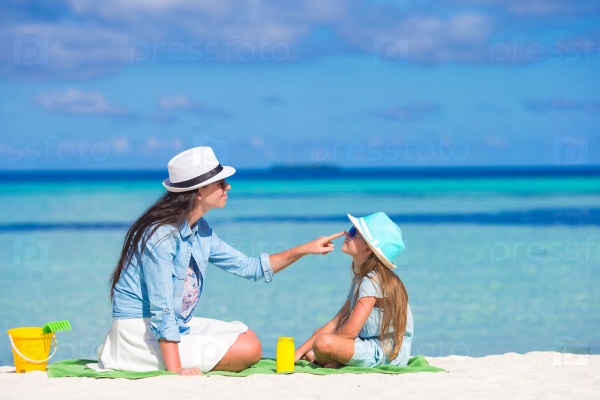 Mother applying sun protection cream to her daughter at tropical beach