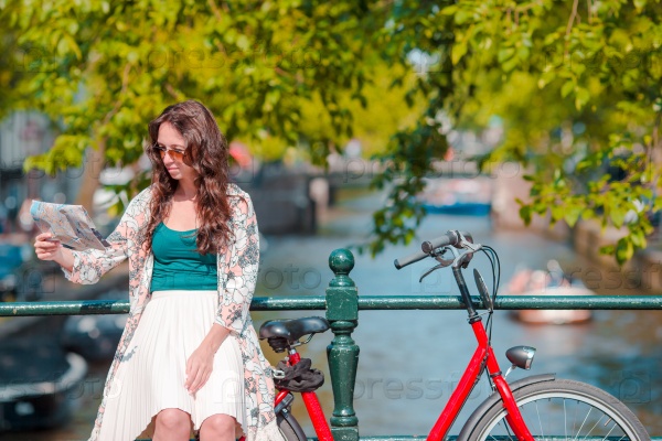 Young woman with city map and bikes in european city