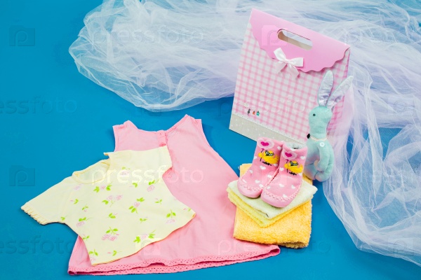 The baby clothes with a gift box on blue background, stock photo