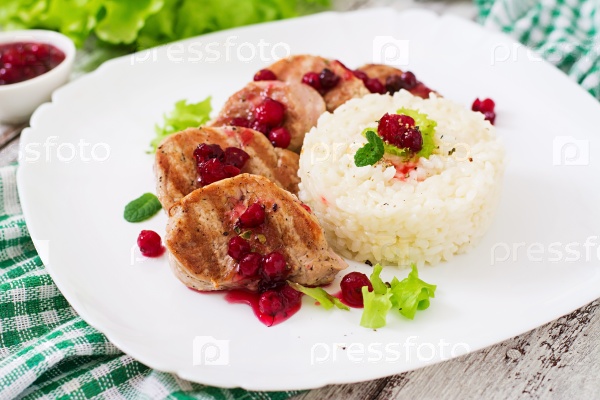 Pork medallions steak with cranberry sauce and a side dish of rice, stock photo