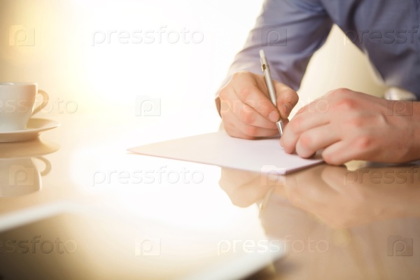 The male hands with a pen and the cup of coffee and notebook, stock photo