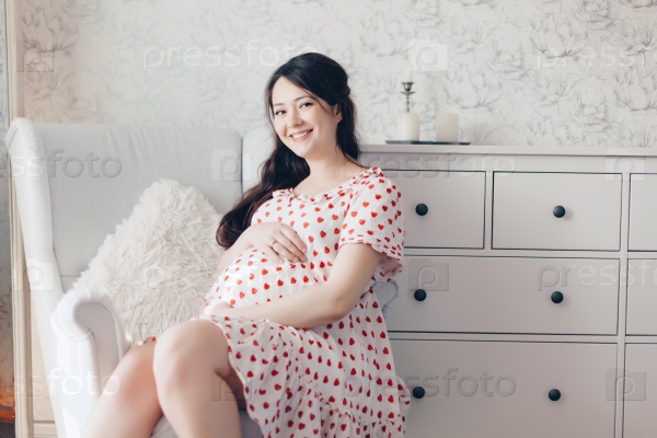 Home portrait of young pregnant woman resting at nursery, stock photo