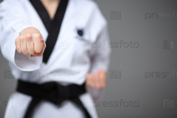 The hand of karate girl in white kimono and black belt training karate over gray background, stock photo