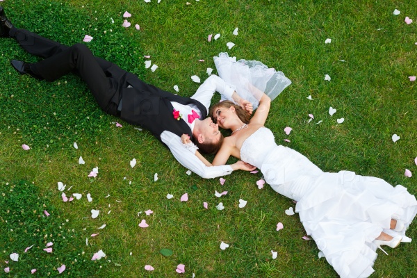 Happy wedding couple lying on green grass