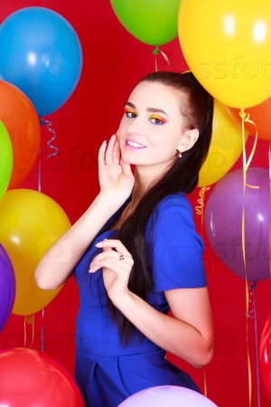 Portrait of a young attractive woman among many bright balloons