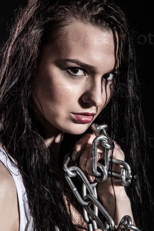Portrait of a beautiful young woman with a steel chain over black background