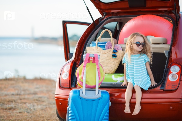 happy and joyful child in car and suitcases background. vacation and car trip concept. freedom and wind. girl traveler. holidays, voyage, sea and beach on background. summer time