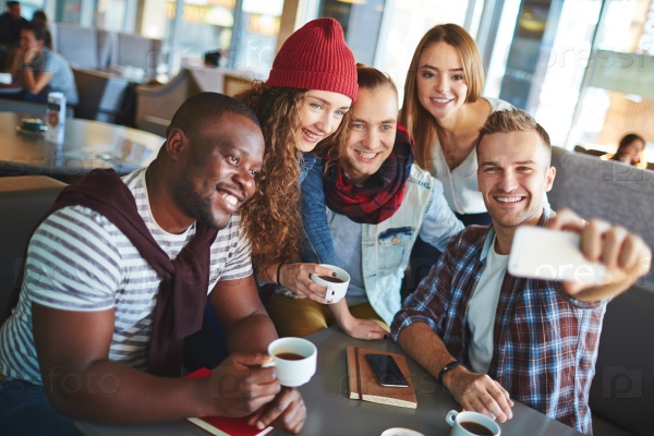 Modern teenage friends making selfie while gathering in cafe, stock photo