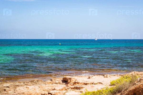 TORREVIEJA, SPAIN - SEPTEMBER 13, 2014: Sailboats floating in sea on horizon, stone coast of Sunny beach, Av de la Purisima, Torrevieja, Valencian Community, Spain, stock photo