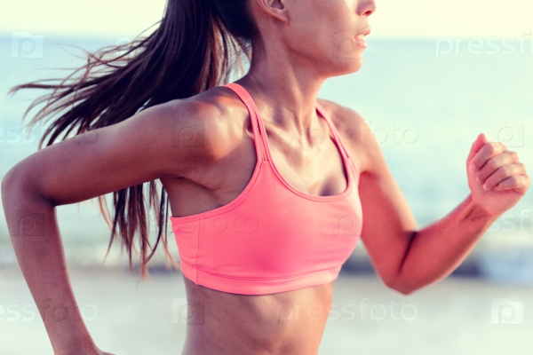 Cardio running workout - Upper body closeup crop of unrecognizable woman runner in fast motion showing pink sports bra activewear clothing in ocean beach nature background.