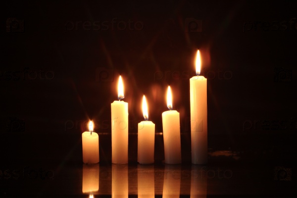 Few lighting candles in a row on dark background, stock photo