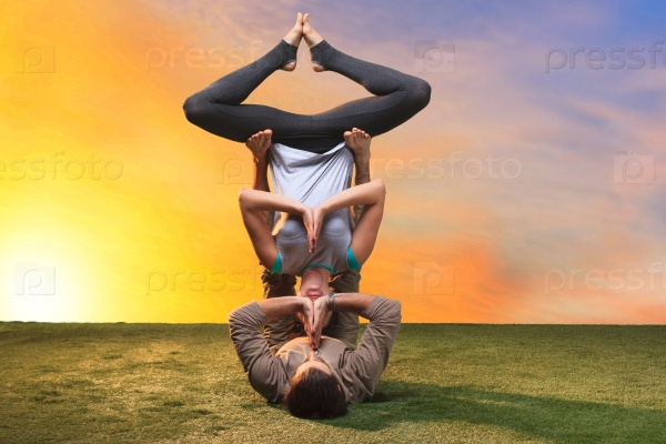 The two people doing yoga exercises against sunset sky, stock photo