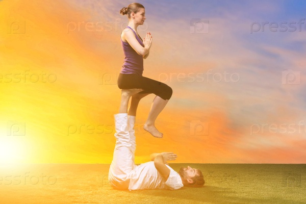 The two people doing yoga exercises against sunset sky, stock photo