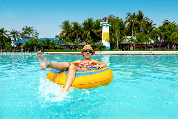 Tween girl relaxing on the inflatable ring in the water park in Thailand