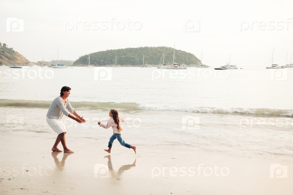 Family walking on the evening beach during sunset, travel photo series. Child running to dad, stock photo