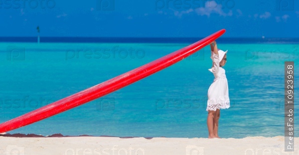 Adorable little girl with red big surfboard during tropical vacation