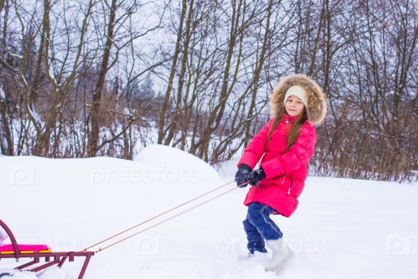 Little girl going sledding in snowy winter day