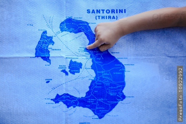 Girl points finger at the map of island of Santorini, Greece