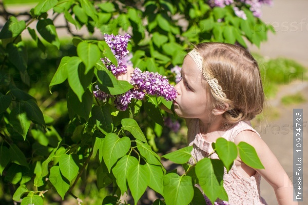 Little adorable girl near white flowers in the park, stock photo