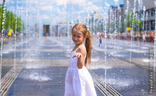 Little happy girl have fun in street fountain at hot sunny day