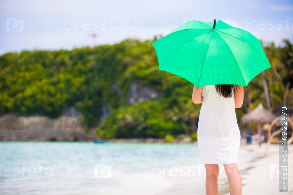 Young girl with green umbrella on white beach