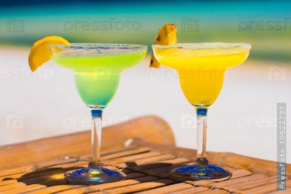 Two tasty alcoholic cocktails on background of turquoise sea