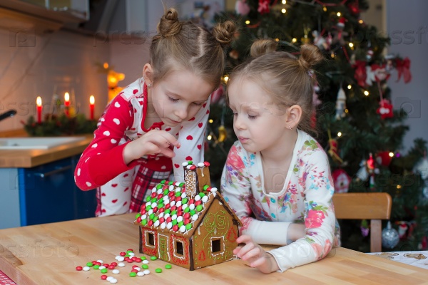 Little adorable girls decorating gingerbread house for Christmas, stock photo