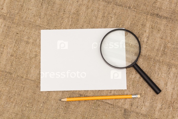 White sheet of paper and magnifying glass, view from above, stock photo