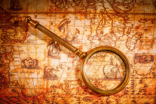 Vintage still life. Vintage magnifying glass lies on an ancient world map in 1565, stock photo
